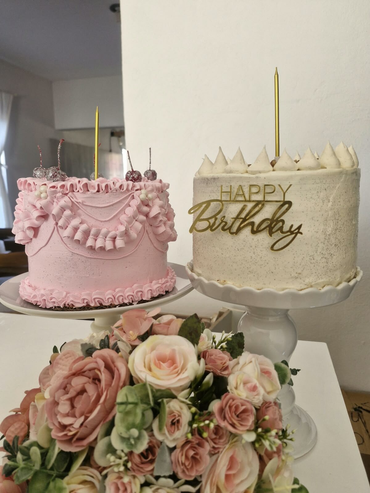 Dos pasteles, uno rosa y uno blanco, con flores