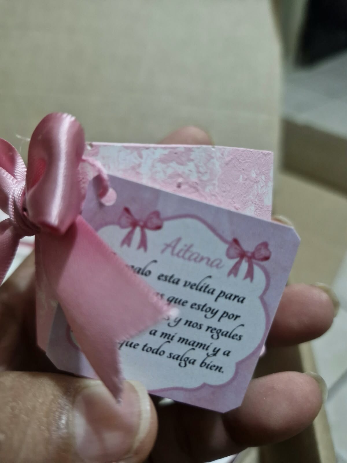 Vela rosa con moño y una tarjeta con mensaje